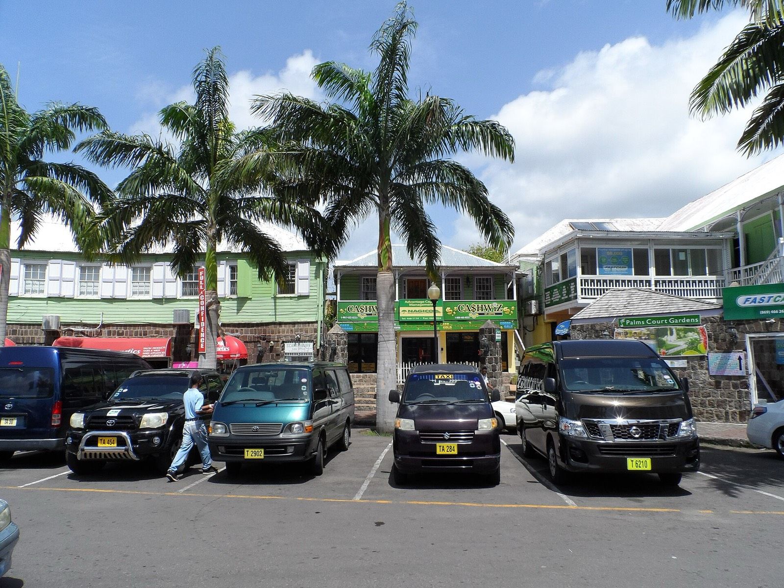 The Circus in Basseterre: palm trees, painted two-storey buildings and a row of taxis with yellow T plates