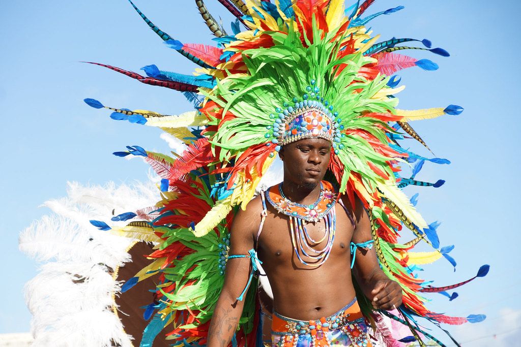 A masquerader in a towering headdress of green, orange and blue feathers at Sugar Mas in St. Kitts